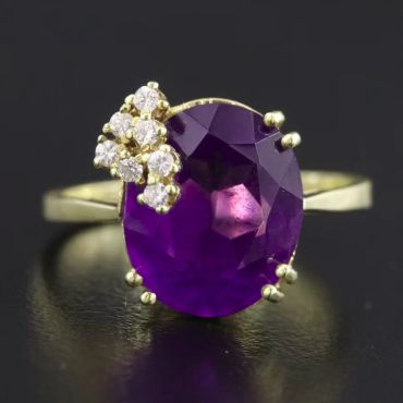 Gold ring with a large purple gemstone and small diamonds.