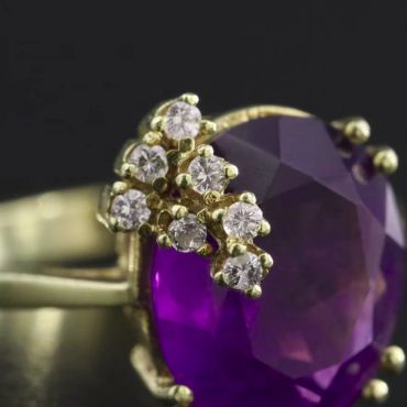 Gold ring with purple gemstone and small diamonds.