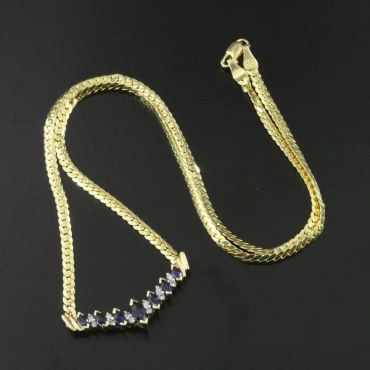 Gold chain necklace with blue stones on a black background.