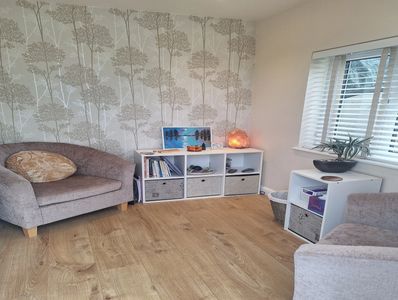 Cozy living room with gray armchairs, wooden floor, and white storage units.
