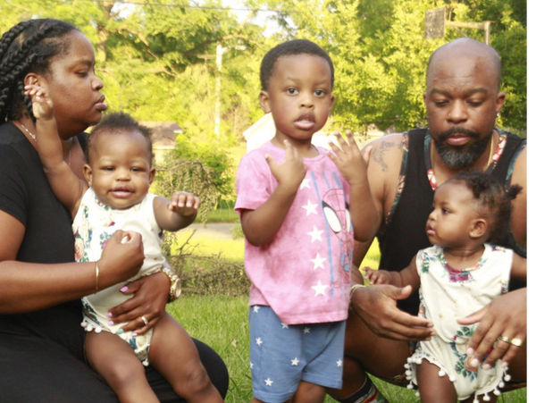 Family of five outdoors on grass with kids and parents.