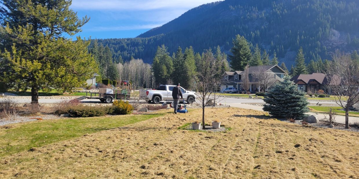 Man mowing a large yard in a mountain neighborhood on a sunny day.