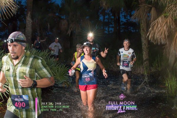 Group of runners running trails at night with headlamps