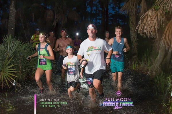 A group of runners running the 10 Mile Night Trail Run.