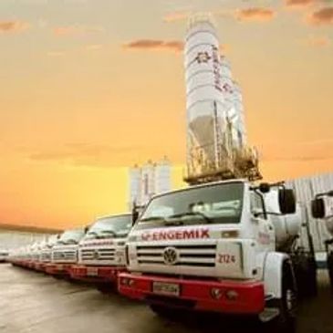 A row of cement mixer trucks lined up at sunset.