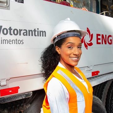 Smiling female worker in safety gear at a construction site.