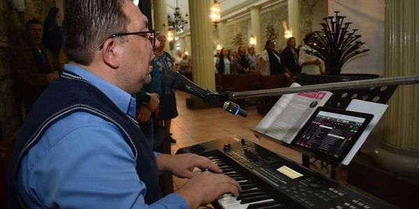 Man playing keyboard and singing in a church setting.
