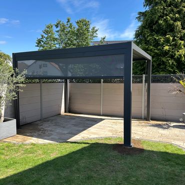 Modern outdoor pergola with a retractable screen in a sunny garden.