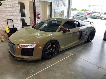 Sleek beige sports car with black rims and orange accents in a garage.