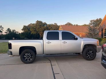 Silver pickup truck parked on a driveway in a suburban neighborhood.