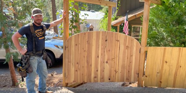 Man standing next to a newly built wooden gate.