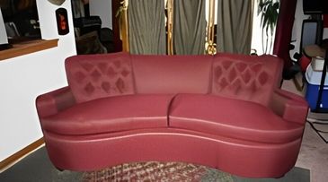 Vintage curved burgundy sofa with tufted backrest