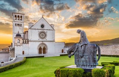 Statue of a knight on horseback in front of a historic church at sunset.