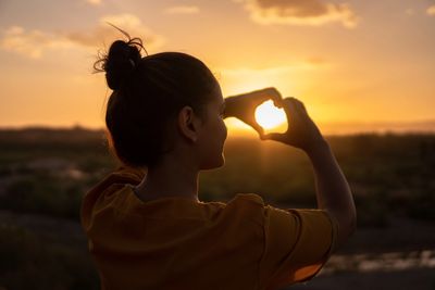 woman with hands in heart shape, representing the health of mindfulness on mental health.