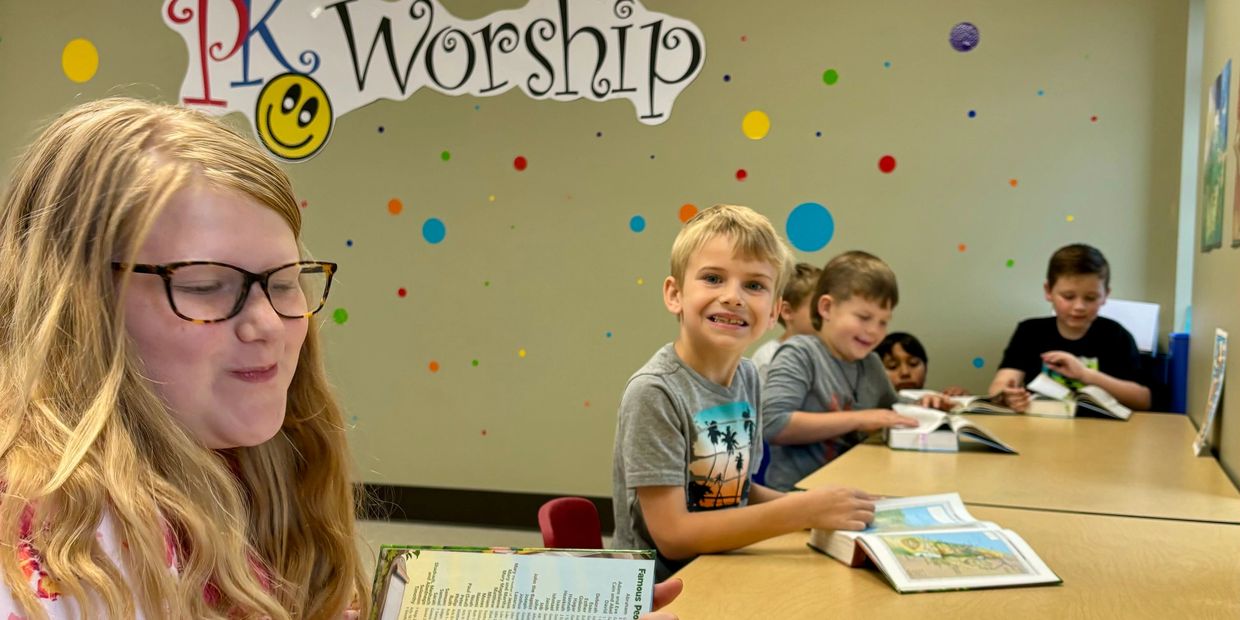 Children reading books together in a colorful classroom.