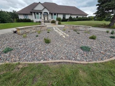 Modern house with landscaped stone garden and two stone benches.