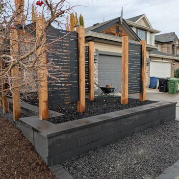 Modern garden privacy screen with wooden posts and black slats in a suburban front yard.