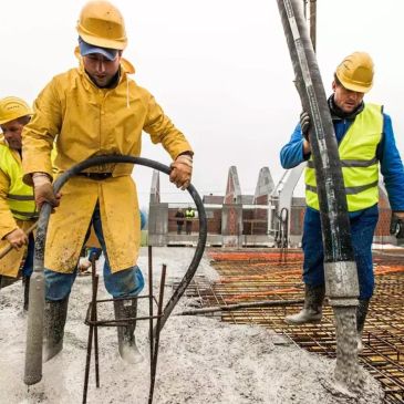 Construction workers pouring concrete on site.