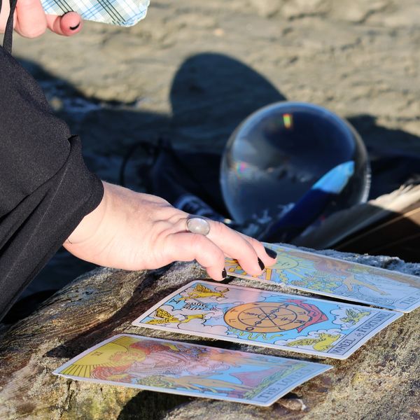 Turning Tides Tarot intuitive reader Alishia Fox on beach with tarot cards on a rock doing a reading