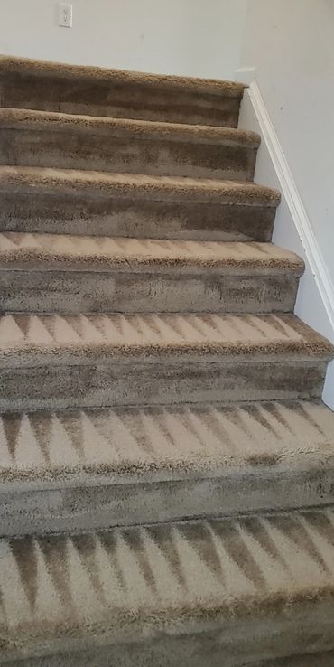 Clean beige carpeted stairs with vacuum lines forming triangular patterns.