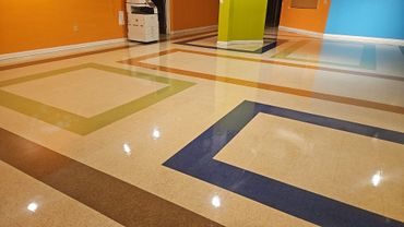 Colorful geometric patterned floor in a brightly painted hallway with orange, blue, and green walls.