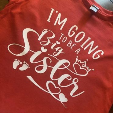 Red t-shirt with white text announcing becoming a big sister.