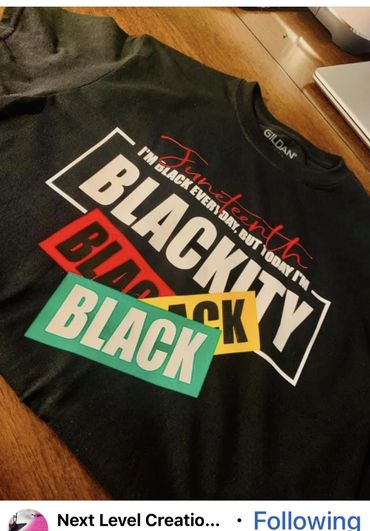 Black sweatshirt with Juneteenth and Blackty text on a wooden table.