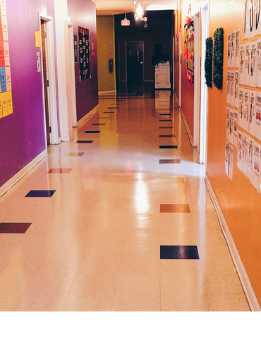 Colorful school hallway with purple and orange walls and tiled floor.