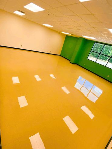 Empty room with shiny yellow floor and green walls reflecting windows.