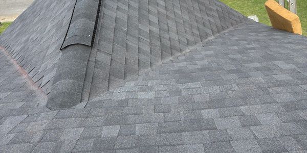 Newly installed dark gray asphalt shingle roof on a suburban house.