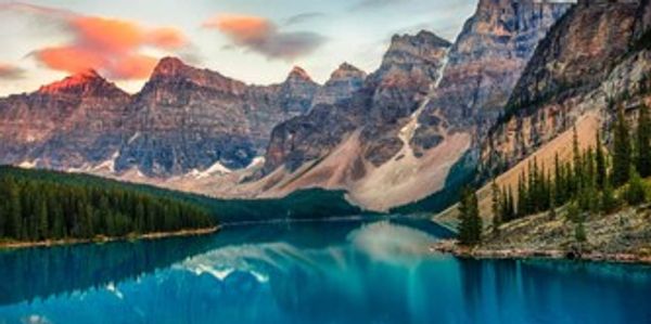 Serene mountain lake reflecting a colorful sunset sky.