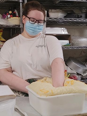 Person wearing a mask kneading dough in a kitchen during the covid era
