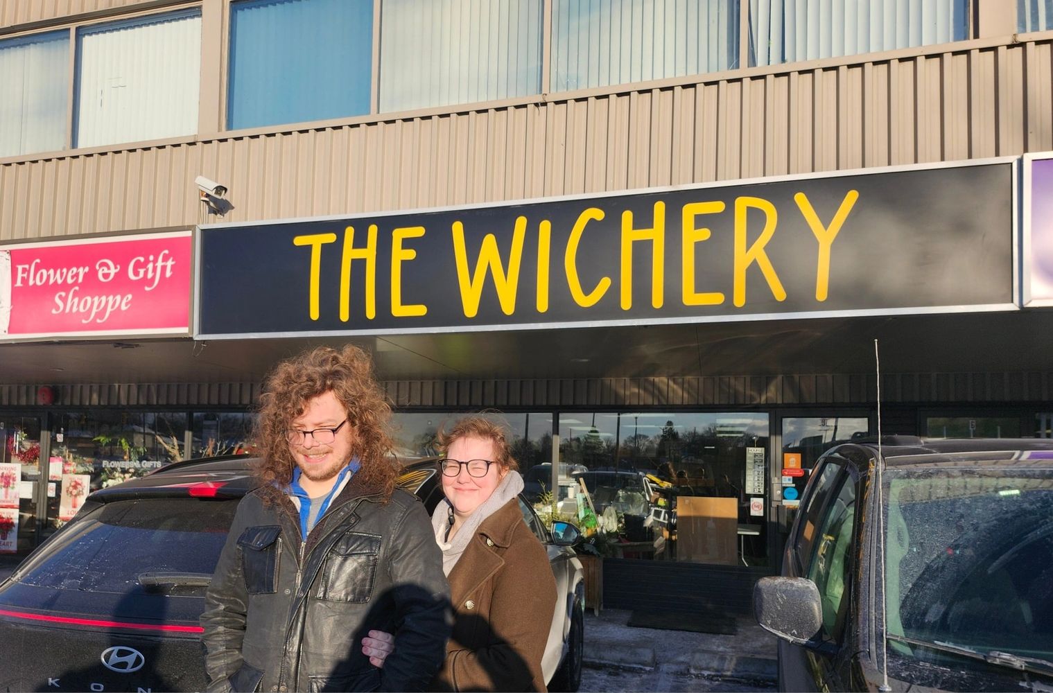 Owners smiling in front of a store named THE WICHERY.