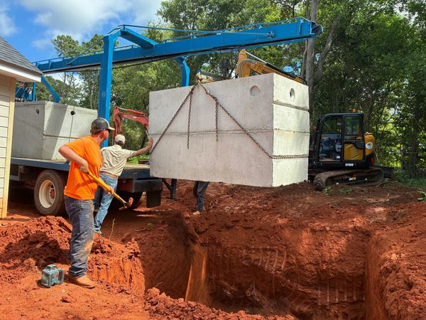 Workers install a large concrete structure into a dug hole.