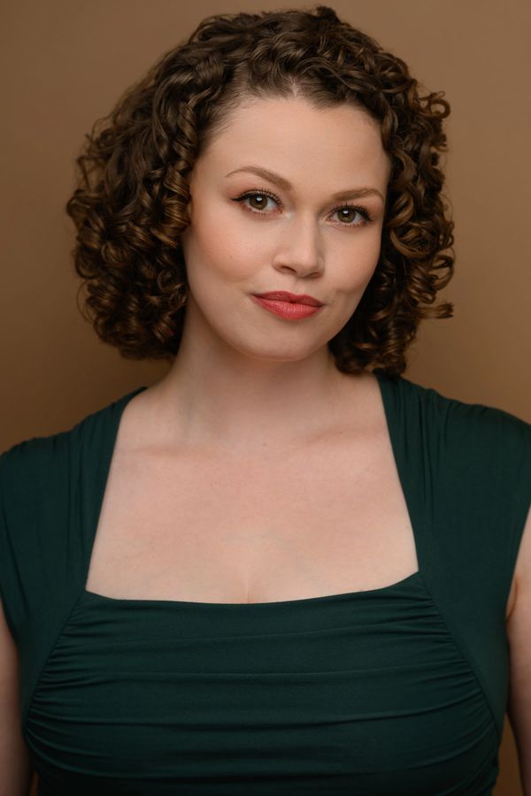 Portrait of a woman with curly hair and a confident smile.