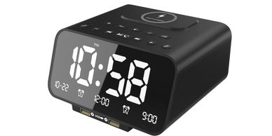 Black digital alarm clock with large white LED display and wireless charging pad.
