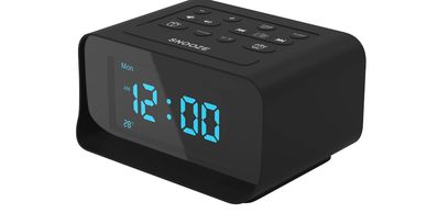 Black digital alarm clock with blue LED display showing 12:00.