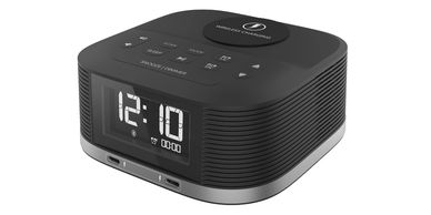 Modern black digital alarm clock with wireless charging pad.