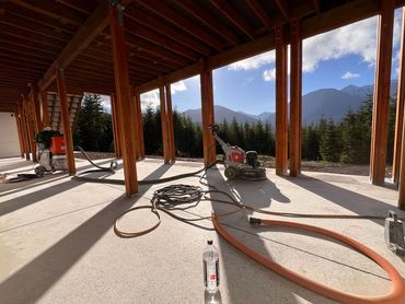 Construction tools on a concrete floor under a wooden structure with mountain views.
