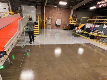 Industrial warehouse with shiny polished floors and a conveyor belt.