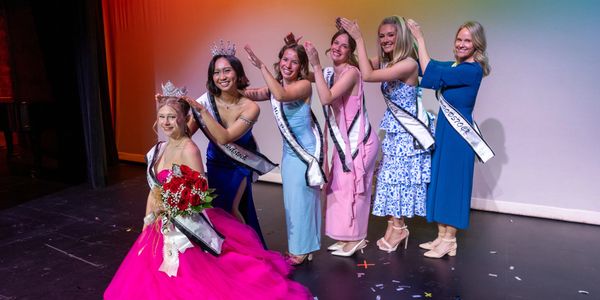 Pageant winners celebrating with crowns and sashes on stage.