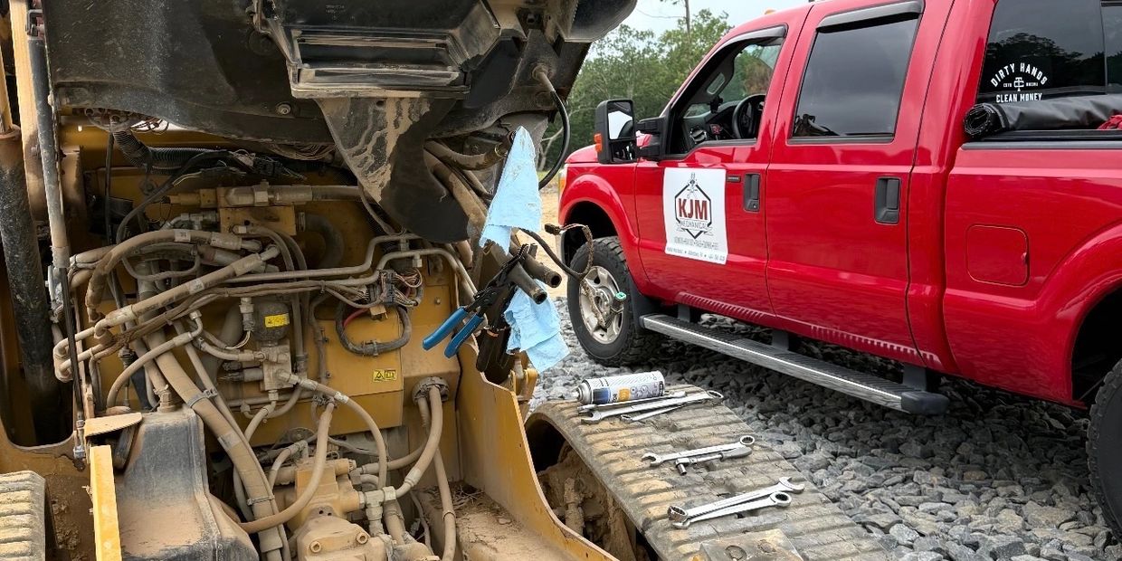 Red pickup truck beside heavy machinery with tools laid out.