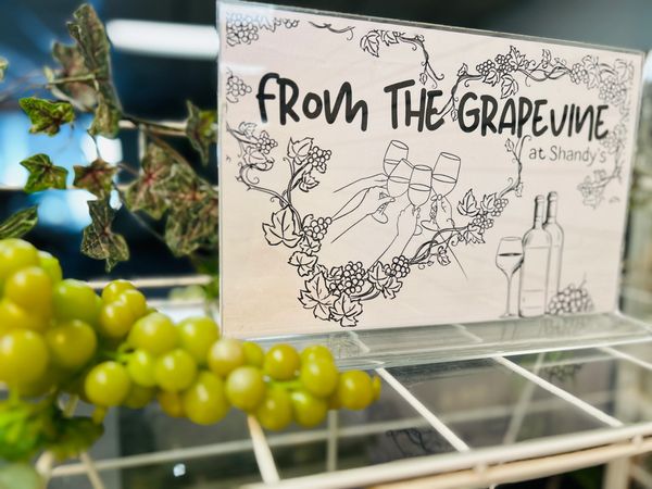 A sign reading 'From The Grapevine at Shandy's' with grapevine illustrations and green grapes in the foreground.