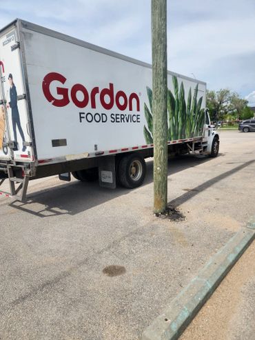 Gordon Food Service truck parked near a utility pole on a sunny day.