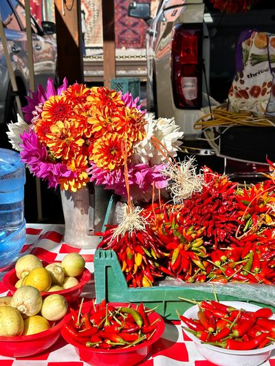 Fresh chili peppers and vibrant flowers at a market stall.