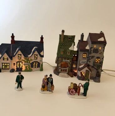 Miniature lit village houses with small figurines in front.