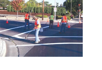 Photo of  street worker striping cross walk lines at an intersection