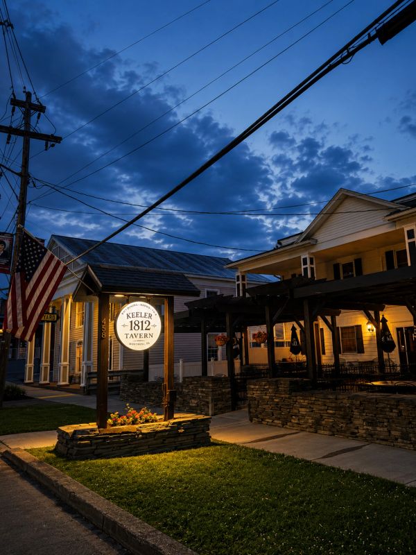 Evening view of Keeler 1812 Tavern with lights on.