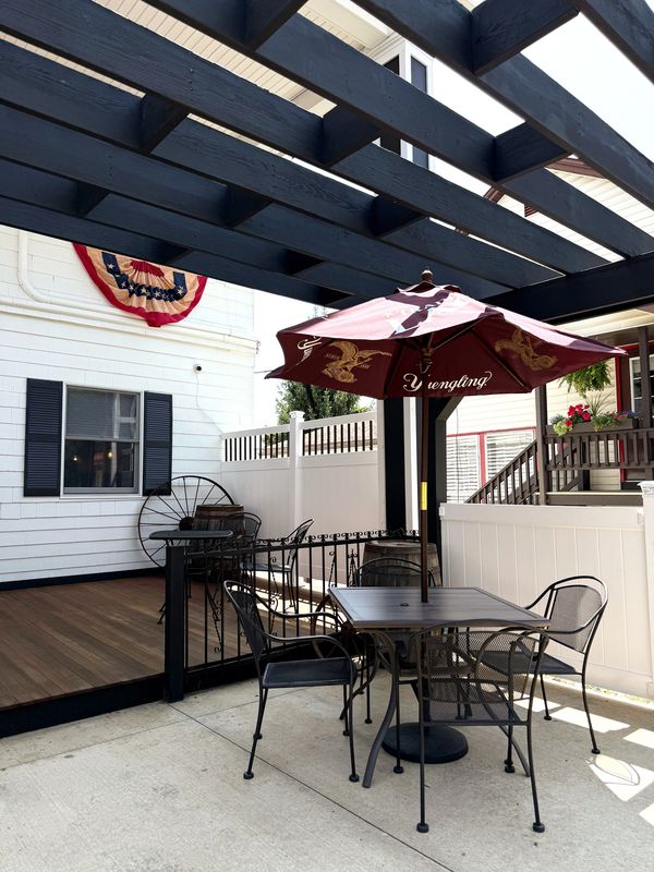 Outdoor patio with umbrella and chairs under pergola.
