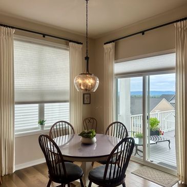 Cozy dining nook with cordless honeycomb shades on window and sliding glass door with side neutral panels.